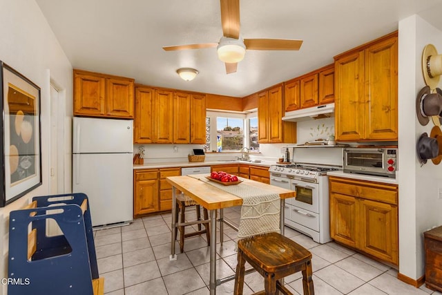 kitchen featuring white appliances, light tile patterned floors, a toaster, light countertops, and under cabinet range hood