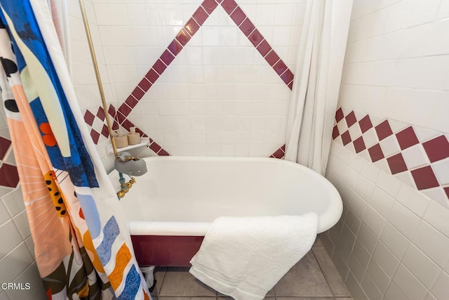 bathroom with tile patterned flooring, tile walls, and a tub