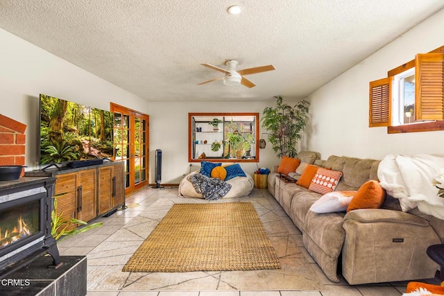 living area featuring light tile patterned floors, a textured ceiling, ceiling fan, and a fireplace