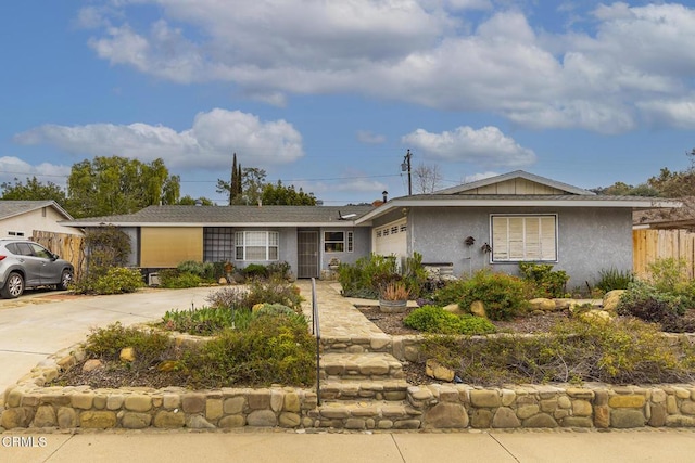 single story home with stucco siding, an attached garage, concrete driveway, and fence