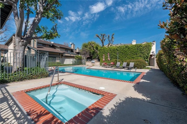 pool with fence, a community hot tub, and a patio