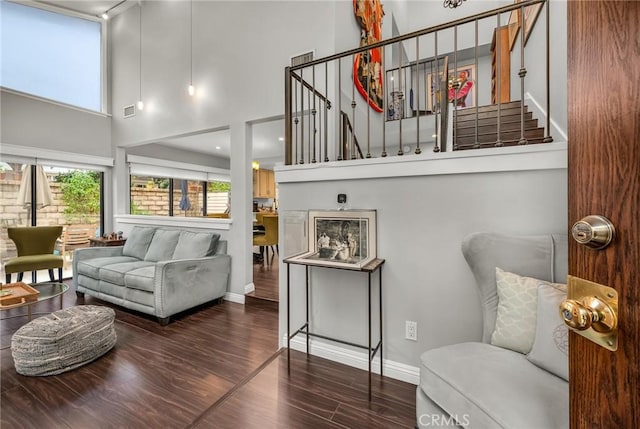 living room featuring wood finished floors, visible vents, a towering ceiling, baseboards, and stairway