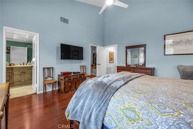 bedroom with a towering ceiling, a spacious closet, wood finished floors, and visible vents