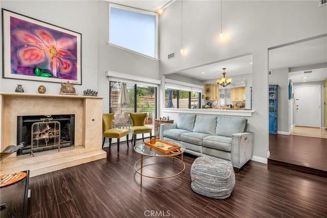 living area featuring a chandelier, visible vents, a fireplace, and wood finished floors