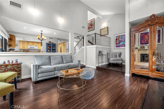 living room featuring a chandelier, visible vents, wood finished floors, high vaulted ceiling, and stairs