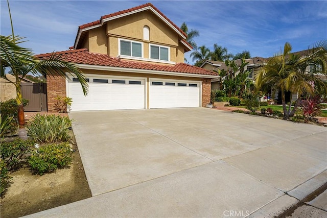 23 Landing, Laguna Niguel, CA 92677 - mediterranean / spanish house featuring concrete driveway, a tiled roof, stucco siding, a garage, and brick siding