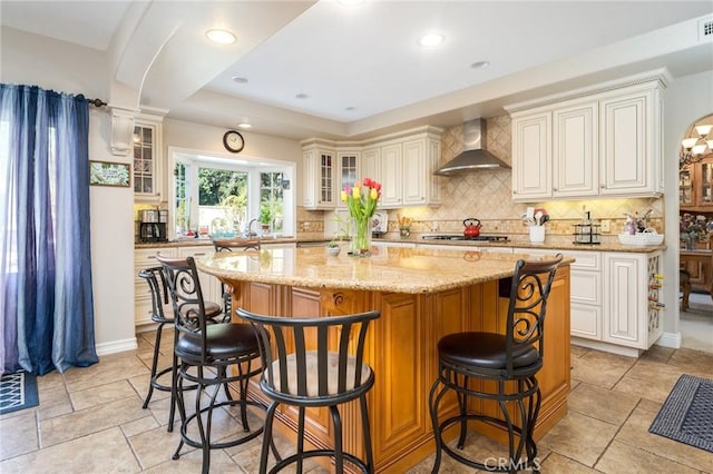 23 Landing, Laguna Niguel, CA 92677 - kitchen with wall chimney exhaust hood, a center island, decorative backsplash, light stone countertops, and a kitchen breakfast bar
