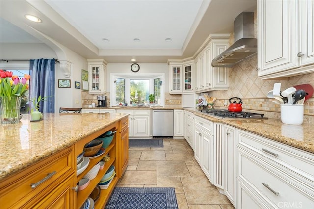 23 Landing, Laguna Niguel, CA 92677 - kitchen with wall chimney range hood, a tray ceiling, decorative backsplash, light stone counters, and appliances with stainless steel finishes
