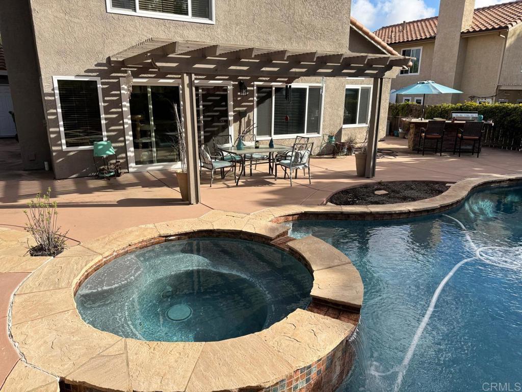 view of swimming pool with a patio, outdoor dining area, a pool with connected hot tub, and a pergola