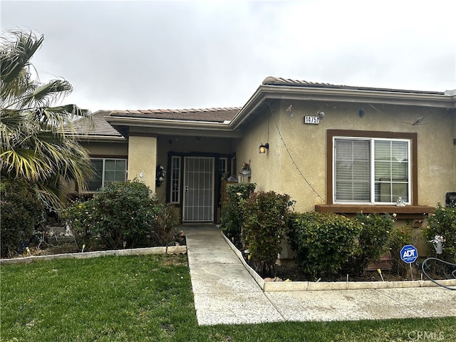 property entrance featuring a yard, a tiled roof, and stucco siding