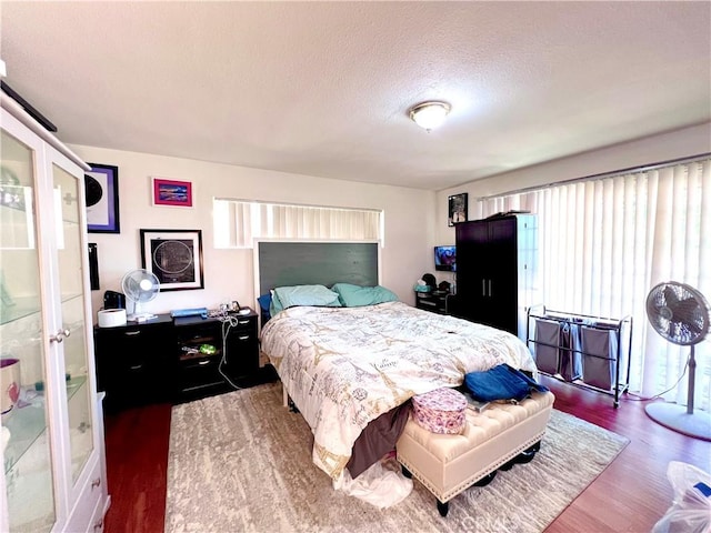 bedroom featuring a textured ceiling, multiple windows, and wood finished floors