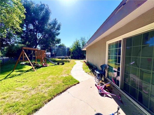 view of yard featuring a patio area, a trampoline, fence, and a playground