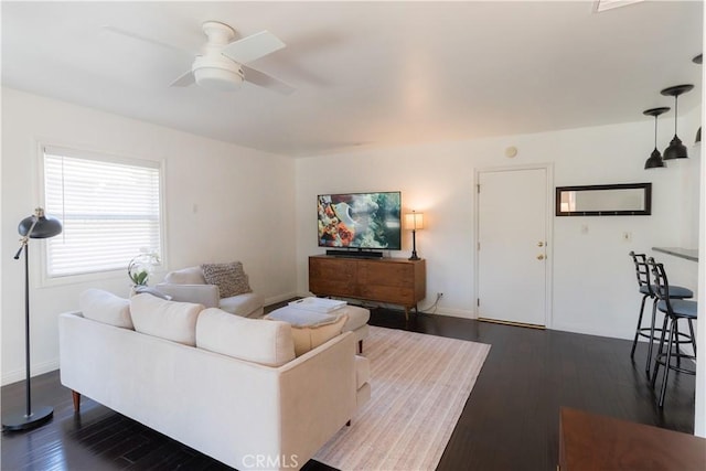 living area with dark wood-style floors, a ceiling fan, and baseboards