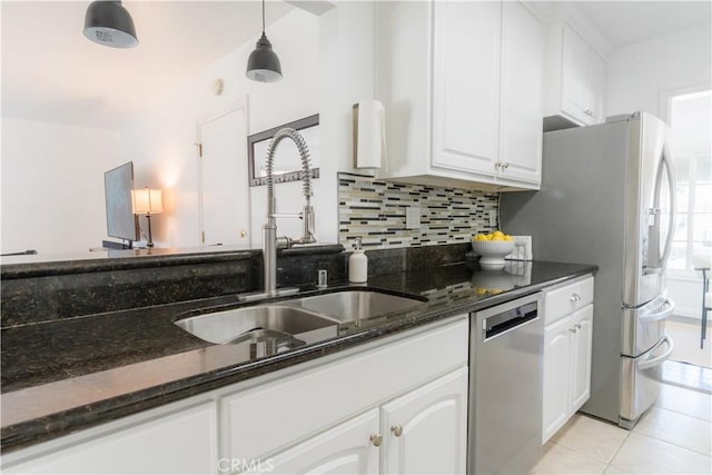 kitchen with tasteful backsplash, dark stone countertops, stainless steel appliances, white cabinetry, and a sink