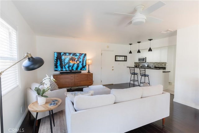 living area with ceiling fan, dark wood-type flooring, visible vents, and baseboards