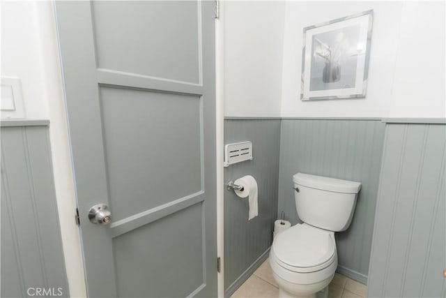 bathroom with tile patterned flooring, a wainscoted wall, and toilet