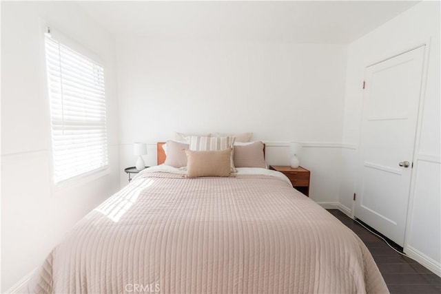 bedroom with dark wood-style floors, multiple windows, and baseboards