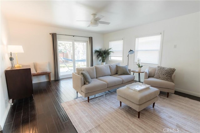 living area featuring a ceiling fan, baseboards, and dark wood-type flooring