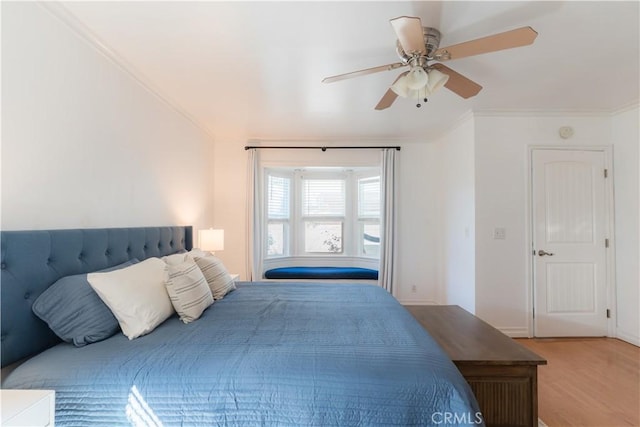 bedroom with light wood-type flooring, baseboards, a ceiling fan, and crown molding