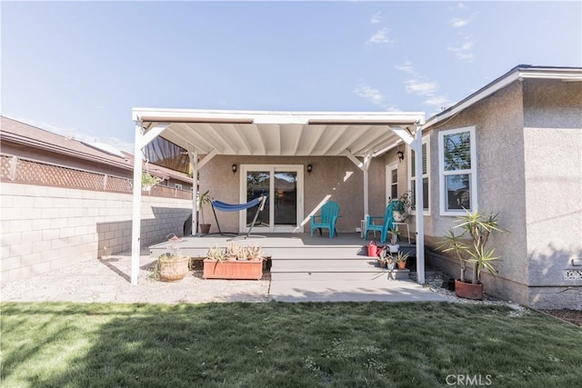 back of property with fence, a yard, a patio, and stucco siding