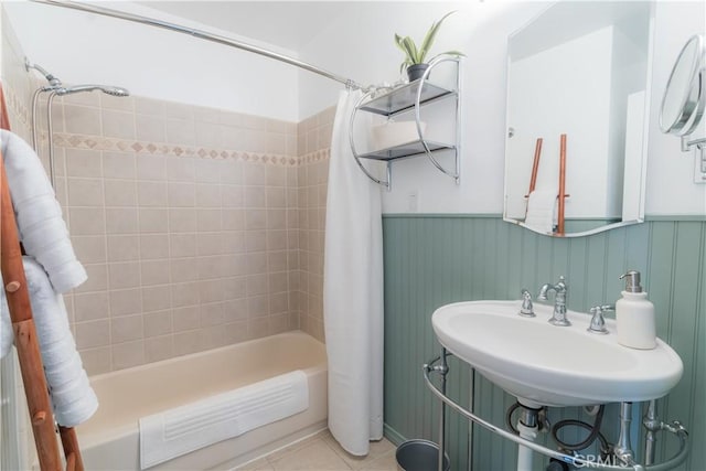 full bathroom with a sink, tile patterned flooring, shower / bath combination with curtain, and wainscoting