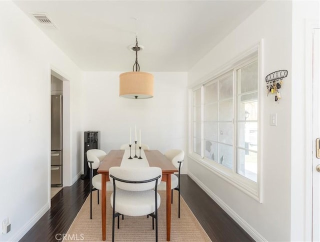 dining space with dark wood-style flooring, visible vents, and baseboards