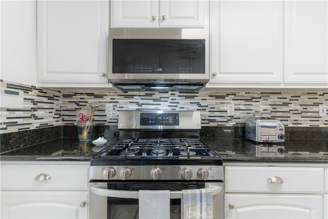 kitchen with white cabinets, appliances with stainless steel finishes, decorative backsplash, and dark stone countertops