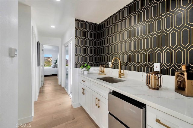 kitchen with a sink, light stone counters, baseboards, recessed lighting, and white cabinetry