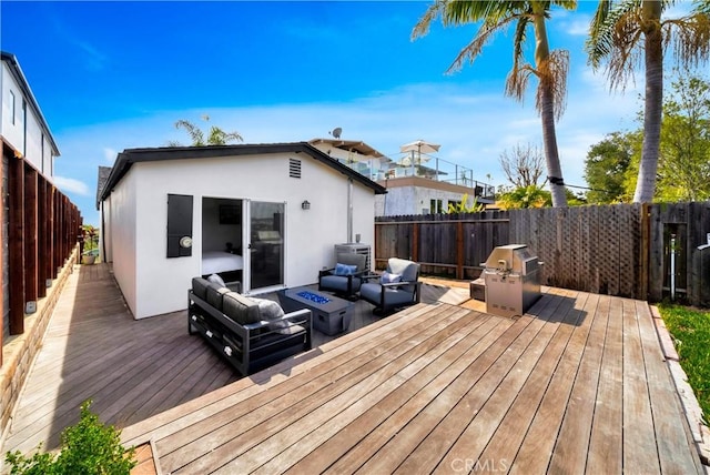 deck featuring a fenced backyard, an outdoor living space with a fire pit, and grilling area