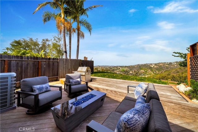 wooden deck featuring an outdoor living space with a fire pit, area for grilling, cooling unit, and fence