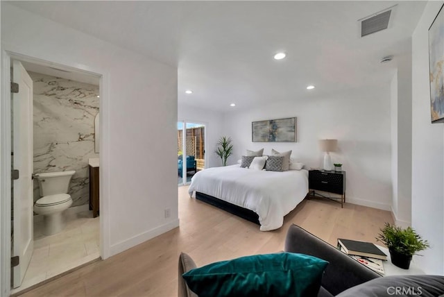 bedroom with ensuite bathroom, wood finished floors, visible vents, and recessed lighting