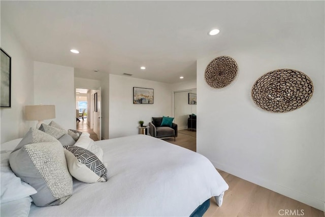 bedroom with recessed lighting, a closet, light wood-style flooring, and baseboards