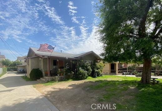 view of front of house featuring concrete driveway, covered porch, and fence