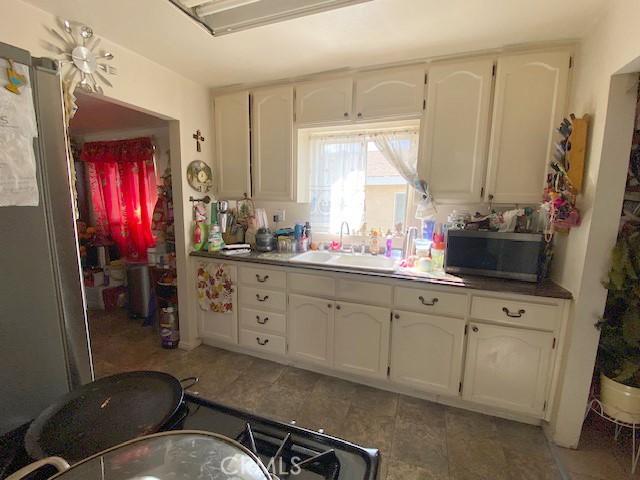 kitchen featuring stainless steel microwave, white cabinets, and a sink