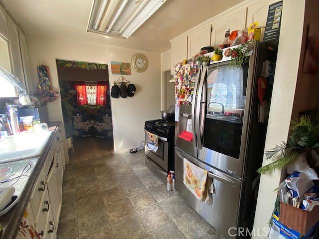 kitchen featuring white cabinets, appliances with stainless steel finishes, and stone finish flooring