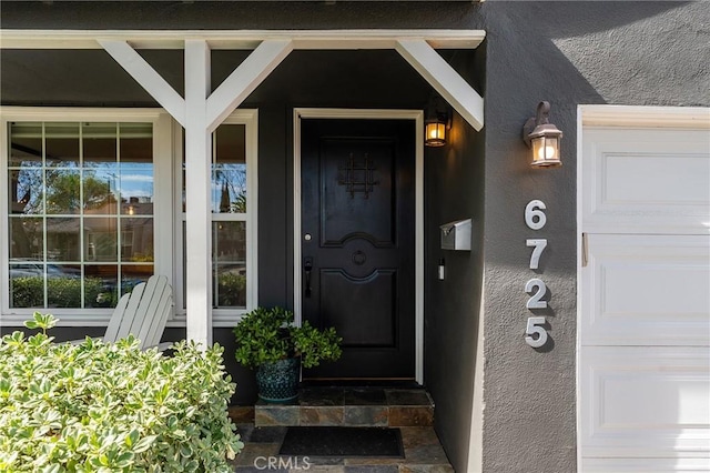 view of exterior entry featuring a garage and stucco siding