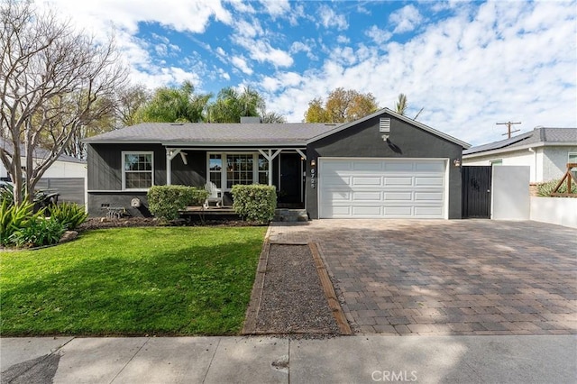 view of front of house with a garage, decorative driveway, a front yard, and stucco siding