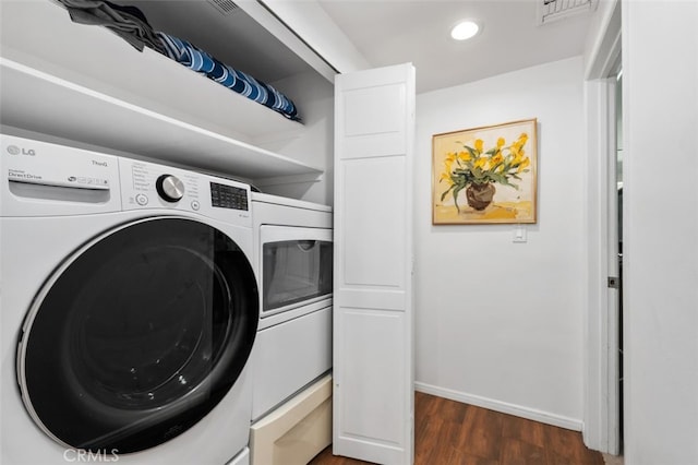 clothes washing area featuring dark wood finished floors, washing machine and clothes dryer, visible vents, laundry area, and baseboards