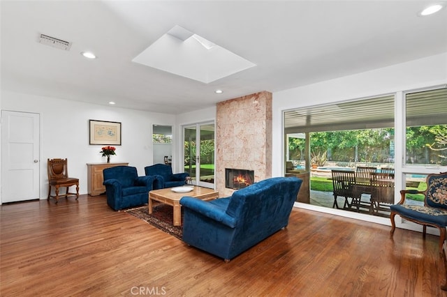 living area featuring a fireplace, wood finished floors, visible vents, and a healthy amount of sunlight