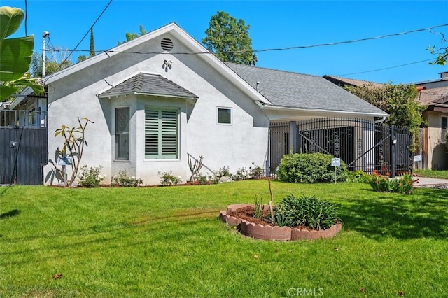 view of front of house featuring a shingled roof, a front lawn, and stucco siding