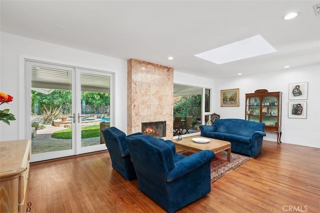 living area featuring recessed lighting, a skylight, light wood-style flooring, and a tile fireplace