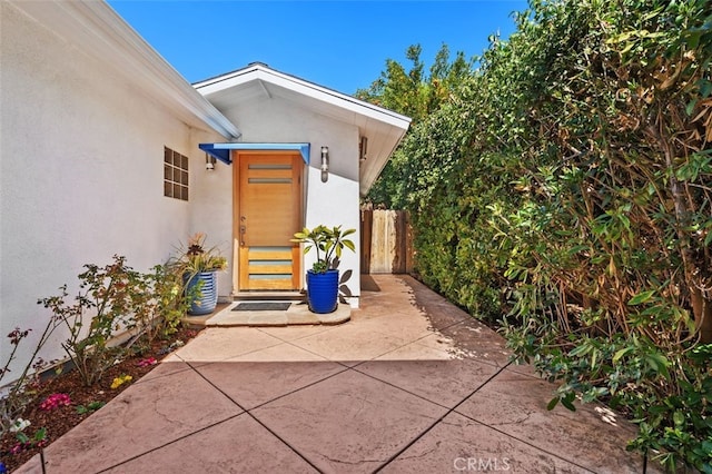 property entrance with fence and stucco siding