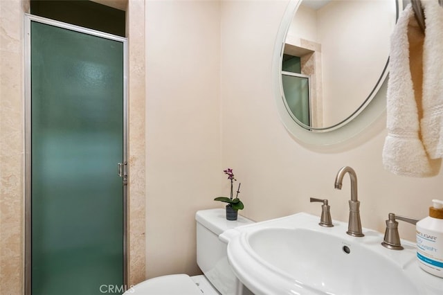 bathroom with a sink, toilet, and a shower stall