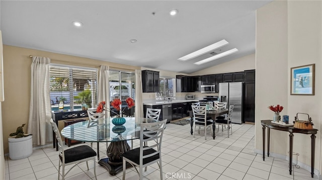 dining area featuring light tile patterned floors, recessed lighting, and vaulted ceiling with skylight