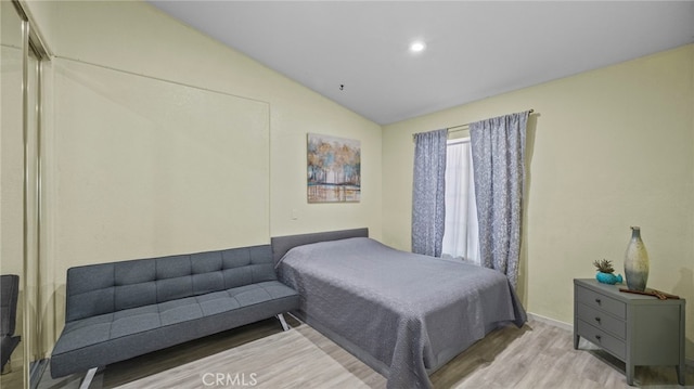 bedroom featuring light wood-style floors and vaulted ceiling