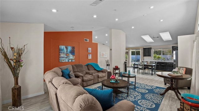 living area with recessed lighting, visible vents, vaulted ceiling with skylight, and light wood-style floors