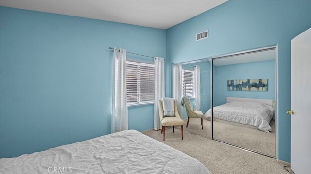 carpeted bedroom with visible vents and a closet