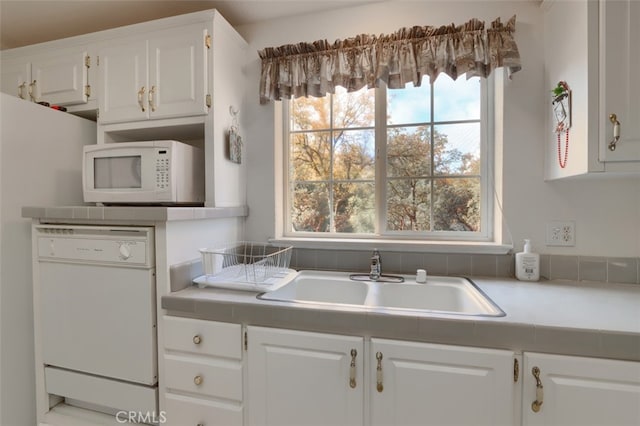 kitchen with light countertops, white appliances, white cabinets, and a sink