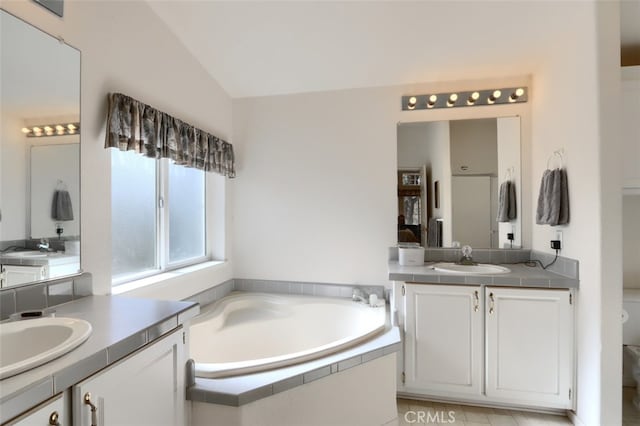 full bathroom featuring lofted ceiling, two vanities, a sink, and a bath