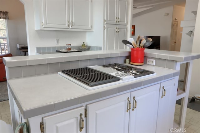 kitchen featuring white gas stovetop, tile counters, a peninsula, and white cabinetry